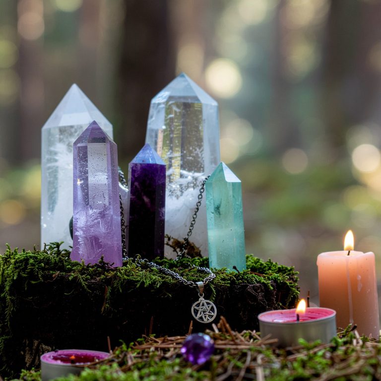 Crystals atop moss with candles in a serene forest setting.
